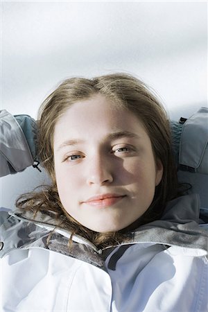 simsearch:695-03378071,k - Teenage girl lying on snow with hands behind head, looking at camera Stock Photo - Premium Royalty-Free, Code: 695-03377027