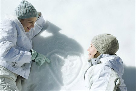 Teenage girls lying on snow, laughing, heart with initials drawn on surface of snow Foto de stock - Sin royalties Premium, Código: 695-03377035