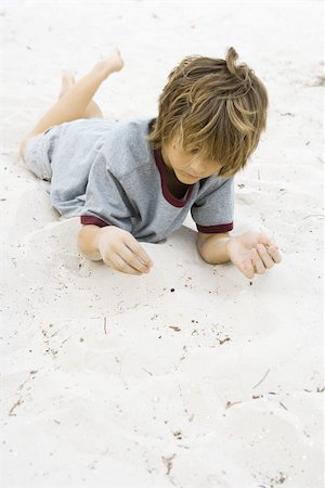simsearch:695-03377206,k - Boy lying on stomach in sand with legs up, looking down Stock Photo - Premium Royalty-Free, Code: 695-03377191