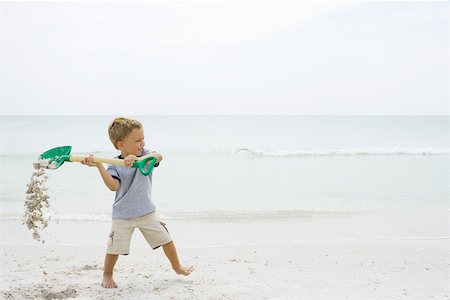 simsearch:695-03377206,k - Young boy at the beach, holding up shovel and spilling sand Foto de stock - Sin royalties Premium, Código: 695-03377217