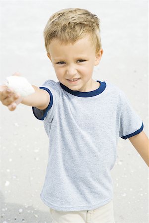 Young boy holding up seashell, smiling at camera Foto de stock - Sin royalties Premium, Código: 695-03377219