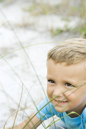 simsearch:695-03380035,k - Young boy in tall grass, smiling, looking away, cropped view Foto de stock - Royalty Free Premium, Número: 695-03377249