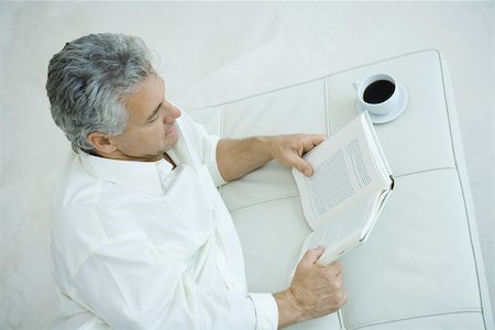 simsearch:632-05400916,k - Mature man lying on side next to coffee cup, reading book, high angle view Foto de stock - Royalty Free Premium, Número: 695-03377284