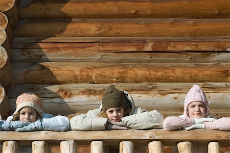 Three preteen or teen girls standing on deck of log cabin, resting heads on hands Stock Photo - Premium Royalty-Free, Code: 695-03377333