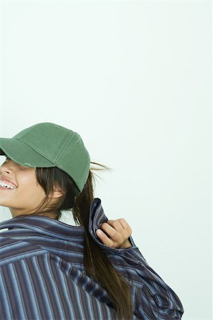 simsearch:400-03929864,k - Teenage girl wearing baseball cap, looking over shoulder, cropped view Stock Photo - Premium Royalty-Free, Code: 695-03377359