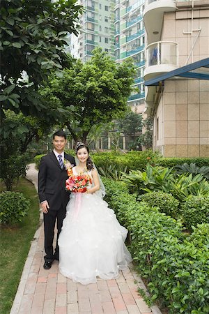 simsearch:695-03377419,k - Bride and groom standing in verdant apartment complex, full length portrait Foto de stock - Sin royalties Premium, Código: 695-03377456