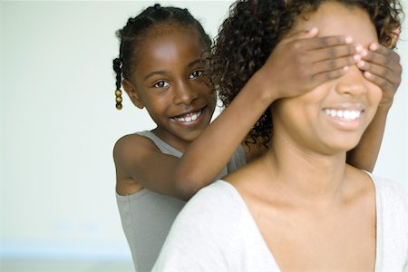 Girl placing hands over her mother's eyes from behind, smiling at camera Stock Photo - Premium Royalty-Free, Code: 695-03377522