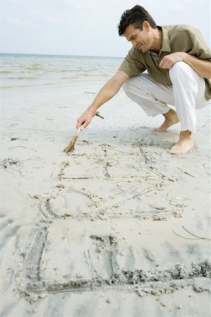 Barefoot man writing word "free" on beach with stick Stock Photo - Premium Royalty-Free, Code: 695-03377559