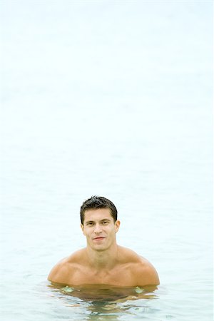 simsearch:632-05604352,k - Muscular man chest deep in water, smiling at camera, front view Stock Photo - Premium Royalty-Free, Code: 695-03377566