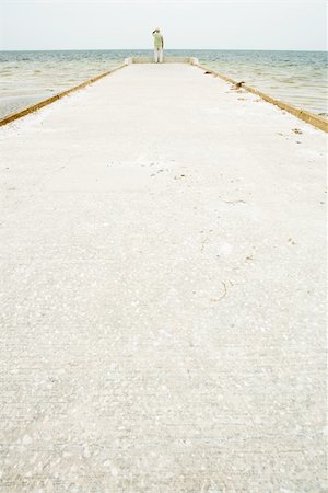 simsearch:649-07521091,k - Senior man standing at end of pier, facing ocean, in distance, rear view Fotografie stock - Premium Royalty-Free, Codice: 695-03377562