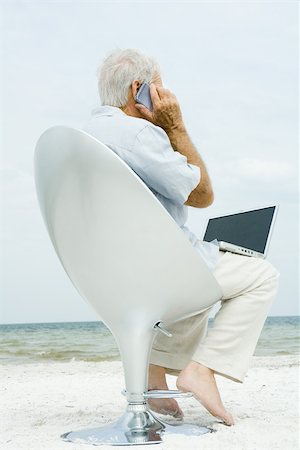 Senior man using laptop and cell phone on beach Stock Photo - Premium Royalty-Free, Code: 695-03377691