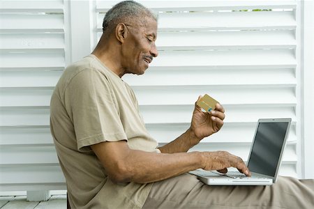 Senior man using laptop, making on-line purchase with credit card Stock Photo - Premium Royalty-Free, Code: 695-03377706
