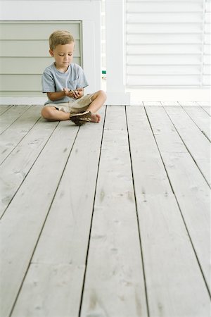 Boy sitting on the ground next to bird's nest, looking down at eggs in his hands Stock Photo - Premium Royalty-Free, Code: 695-03377784