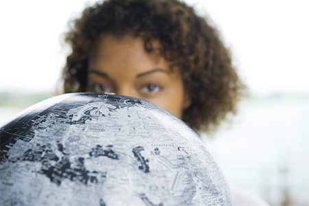 Woman looking over globe at camera, cropped view Stock Photo - Premium Royalty-Free, Code: 695-03377808
