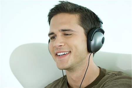 fossetta - Young man listening to headphones, smiling, close-up Fotografie stock - Premium Royalty-Free, Codice: 695-03377898