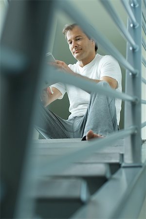 Man sitting on stairs reading book, low angle view Stock Photo - Premium Royalty-Free, Code: 695-03377905