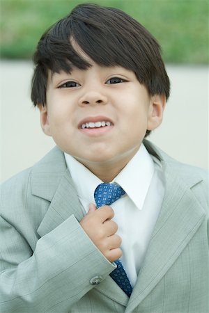 dress up pretend grow up - Young boy dressed in suit, adjusting tie, looking at camera Stock Photo - Premium Royalty-Free, Code: 695-03377929