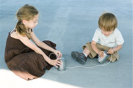 stringing - Frère et sœur, assis sur le sol, jouant à l'étain peut téléphoner Photographie de stock - Premium Libres de Droits, Code: 695-03378026