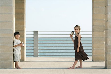 Deux jeunes amis, jouer avec des boîtes de conserve de téléphone ensemble, fille regardant la caméra Photographie de stock - Premium Libres de Droits, Code: 695-03378036