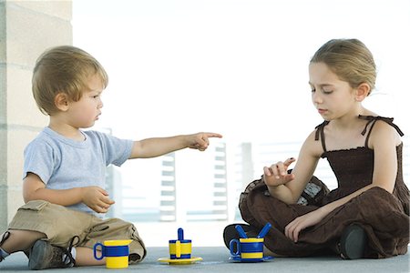 Siblings sitting on the ground together, brother pointing a sister, sister looking down at finger Stock Photo - Premium Royalty-Free, Code: 695-03378033