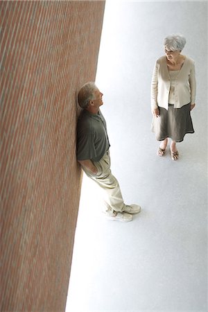 simsearch:695-03379005,k - Couple de parler ensemble, homme appuyé contre le mur avec les mains dans les poches, vue grand angle Photographie de stock - Premium Libres de Droits, Code: 695-03378040