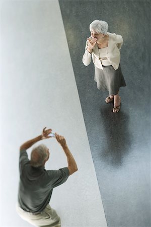 Man holding up digital camera, wife blowing a kiss, viewed from directly above Fotografie stock - Premium Royalty-Free, Codice: 695-03378043