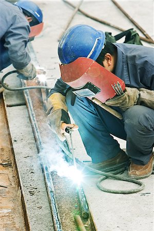 simsearch:695-03378136,k - Worker using welding torch at construction site, side view Fotografie stock - Premium Royalty-Free, Codice: 695-03378144