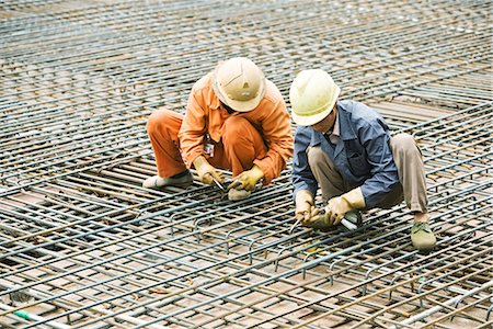 Construction workers crouching on steel framework, both looking down Stock Photo - Premium Royalty-Free, Code: 695-03378141
