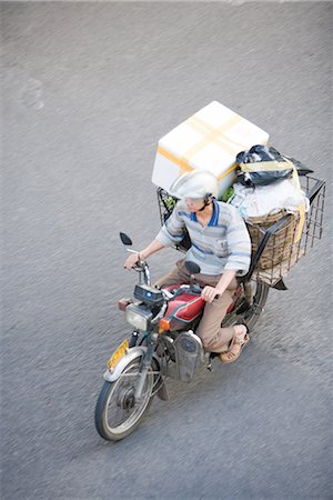 simsearch:695-03378158,k - Man riding moped loaded with boxes, high angle view Fotografie stock - Premium Royalty-Free, Codice: 695-03378159