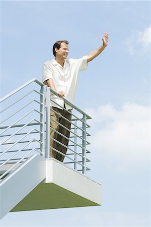 simsearch:632-01828538,k - Man leaning against railing, waving, low angle view Stock Photo - Premium Royalty-Free, Code: 695-03378169