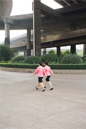 China, Guangzhou, two woman wearing matching uniforms walking under bridge, rear view Stock Photo - Premium Royalty-Free, Code: 695-03378161