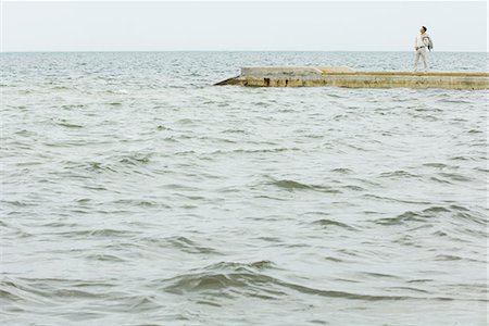 In the distance, man standing on jetty, surrounded by sea Stock Photo - Premium Royalty-Free, Code: 695-03378195