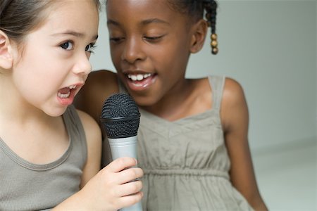 simsearch:632-01785132,k - Two little girls singing into microphone together, close-up Foto de stock - Sin royalties Premium, Código: 695-03378311
