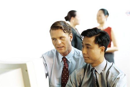 simsearch:695-03374588,k - Two businessmen looking at desktop computer together, women standing in background Stock Photo - Premium Royalty-Free, Code: 695-03378348