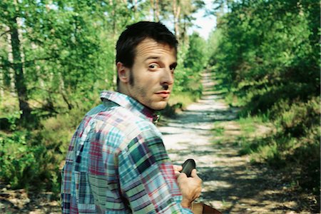 Man walking on path in woods, looking over shoulder at camera, close-up Stock Photo - Premium Royalty-Free, Code: 695-03378367