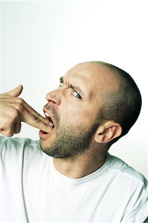 depressed body language - Man making gun gesture, holding fingers in mouth, looking at camera, side view Stock Photo - Premium Royalty-Free, Code: 695-03378383