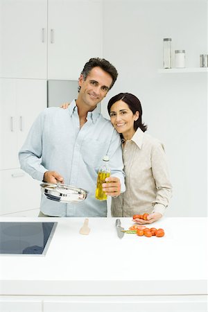 simsearch:693-07912779,k - Couple cooking together in kitchen, both smiling at camera Foto de stock - Sin royalties Premium, Código: 695-03378468