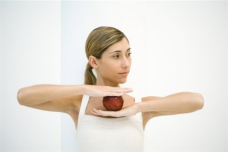 Young woman holding apple, arms raised, looking away Foto de stock - Sin royalties Premium, Código: 695-03378484