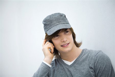 simsearch:695-03380514,k - Young man using cell phone, looking away, smiling, close-up Stock Photo - Premium Royalty-Free, Code: 695-03378491