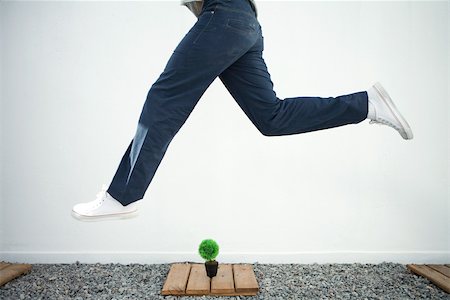 running forward - Man jumping in the air over bonsai, side view, cropped Stock Photo - Premium Royalty-Free, Code: 695-03378506