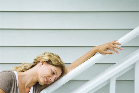 simsearch:695-03377942,k - Woman leaning against railing, head resting on arm, smiling, side view Foto de stock - Royalty Free Premium, Número: 695-03378537