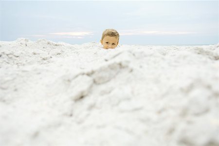 simsearch:632-03193343,k - Little boy at the beach, peeking over sand, smiling Foto de stock - Royalty Free Premium, Número: 695-03378540