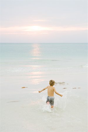 simsearch:695-05768252,k - Little boy running at the beach, arms out, rear view Fotografie stock - Premium Royalty-Free, Codice: 695-03378542
