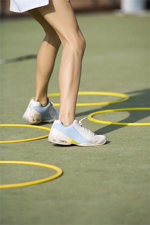 skinny teen girl - Teenage girl in tennis shoes standing beside plastic hoops, low angle view, cropped Foto de stock - Sin royalties Premium, Código: 695-03378564