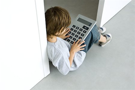 Little boy sitting on the ground, playing with large calculator, high angle view Stock Photo - Premium Royalty-Free, Code: 695-03378582