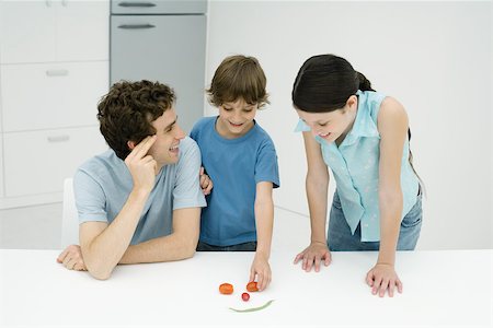 simsearch:695-03379687,k - Father and two children in kitchen, making smiley face out of vegetables Stock Photo - Premium Royalty-Free, Code: 695-03378605