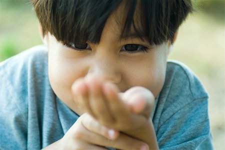 Little boy looking down at cupped hand, close-up Stock Photo - Premium Royalty-Free, Code: 695-03378644