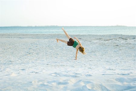 simsearch:695-03373971,k - Little girl doing cartwheel at the beach, rear view Foto de stock - Royalty Free Premium, Número: 695-03378649