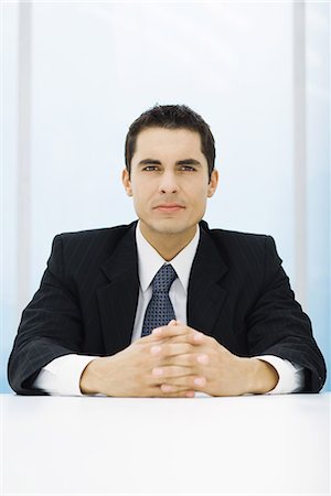 simsearch:632-03403439,k - Businessman sitting at table with clasped hands, looking at camera Fotografie stock - Premium Royalty-Free, Codice: 695-03378684