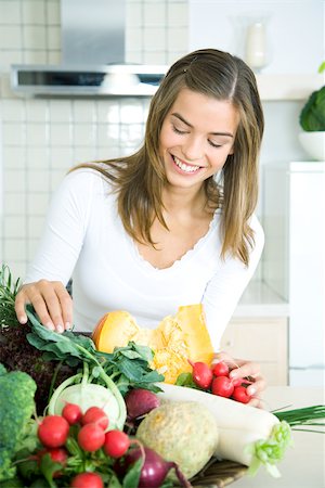 simsearch:633-01272776,k - Young woman in kitchen, looking down at assorted fresh vegetables, smiling Foto de stock - Royalty Free Premium, Número: 695-03378746